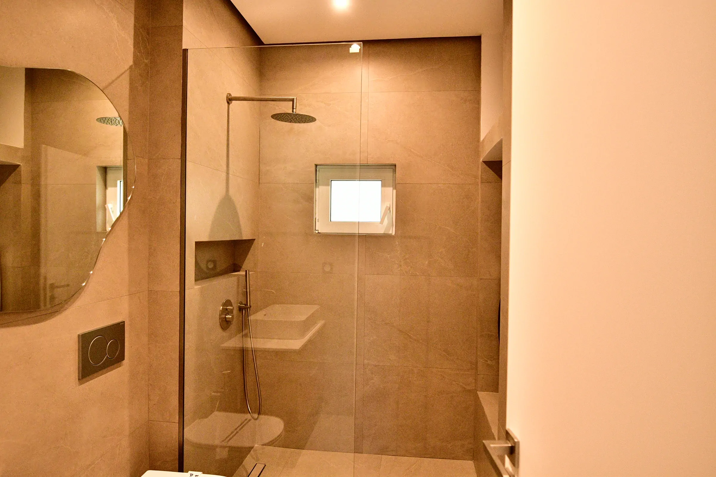 Stone-effect tiles, clear shower glass and a circular rain shower.