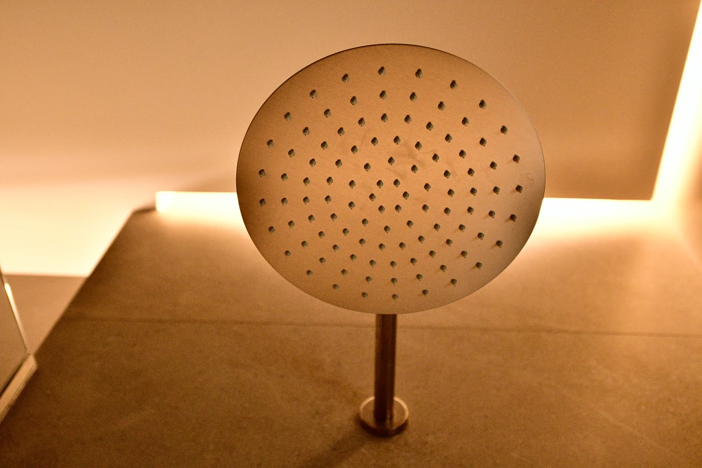 A close view of the stainless-steel shower head and its precise installation.