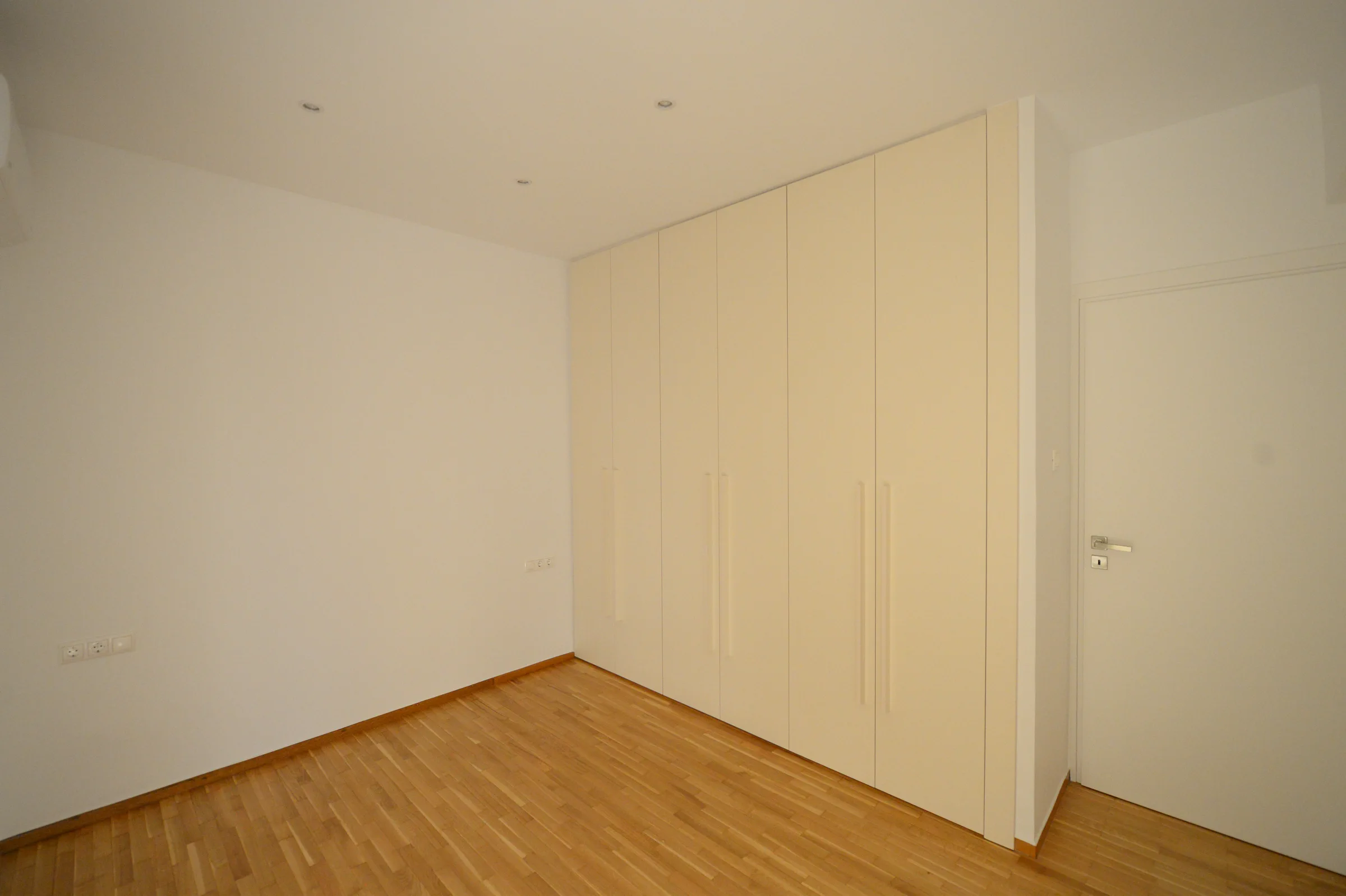 Full-height white doors create a calm, continuous elevation.
