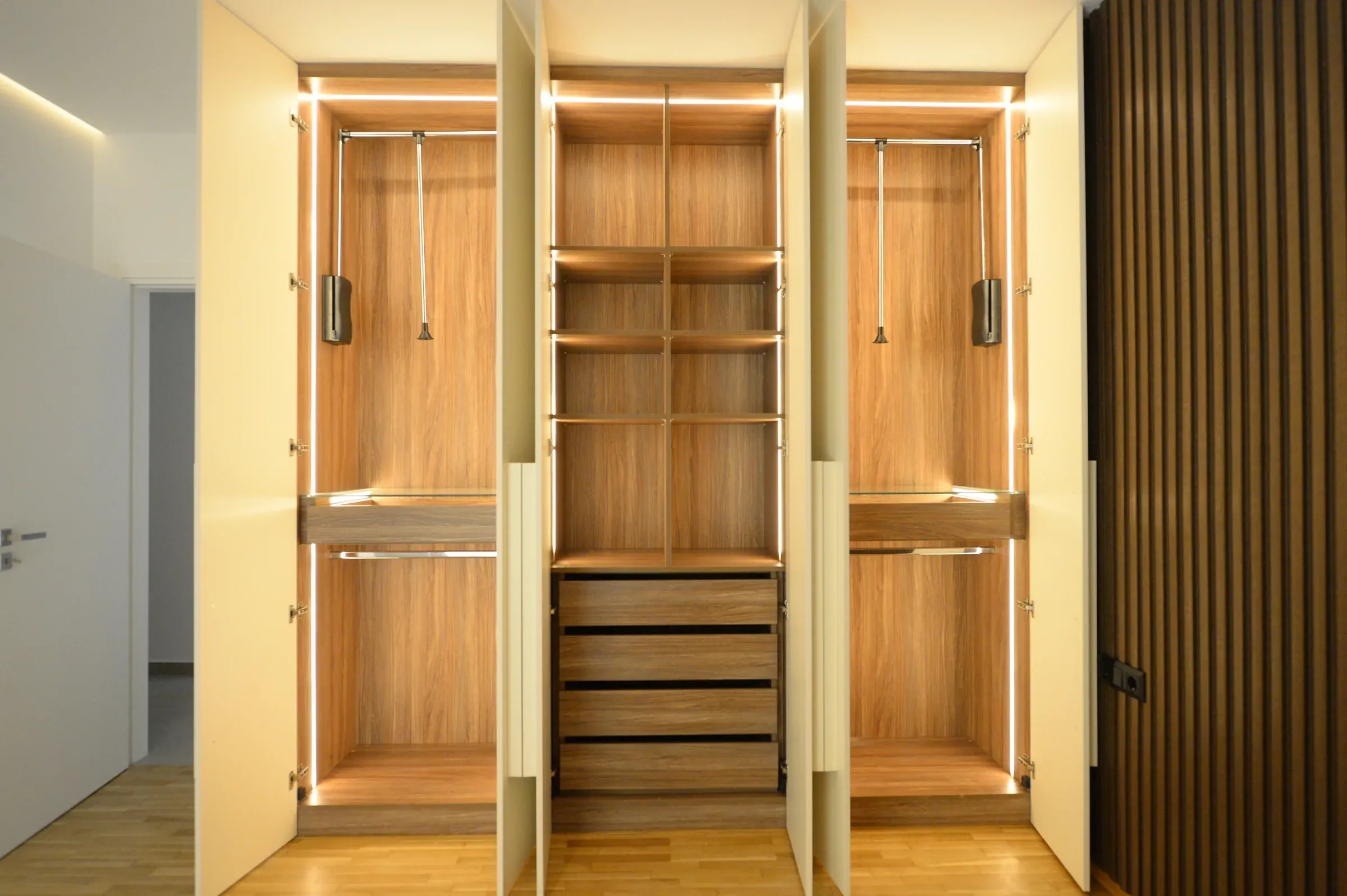 Timber shelves, drawers and hanging rails are lit with integrated LEDs.