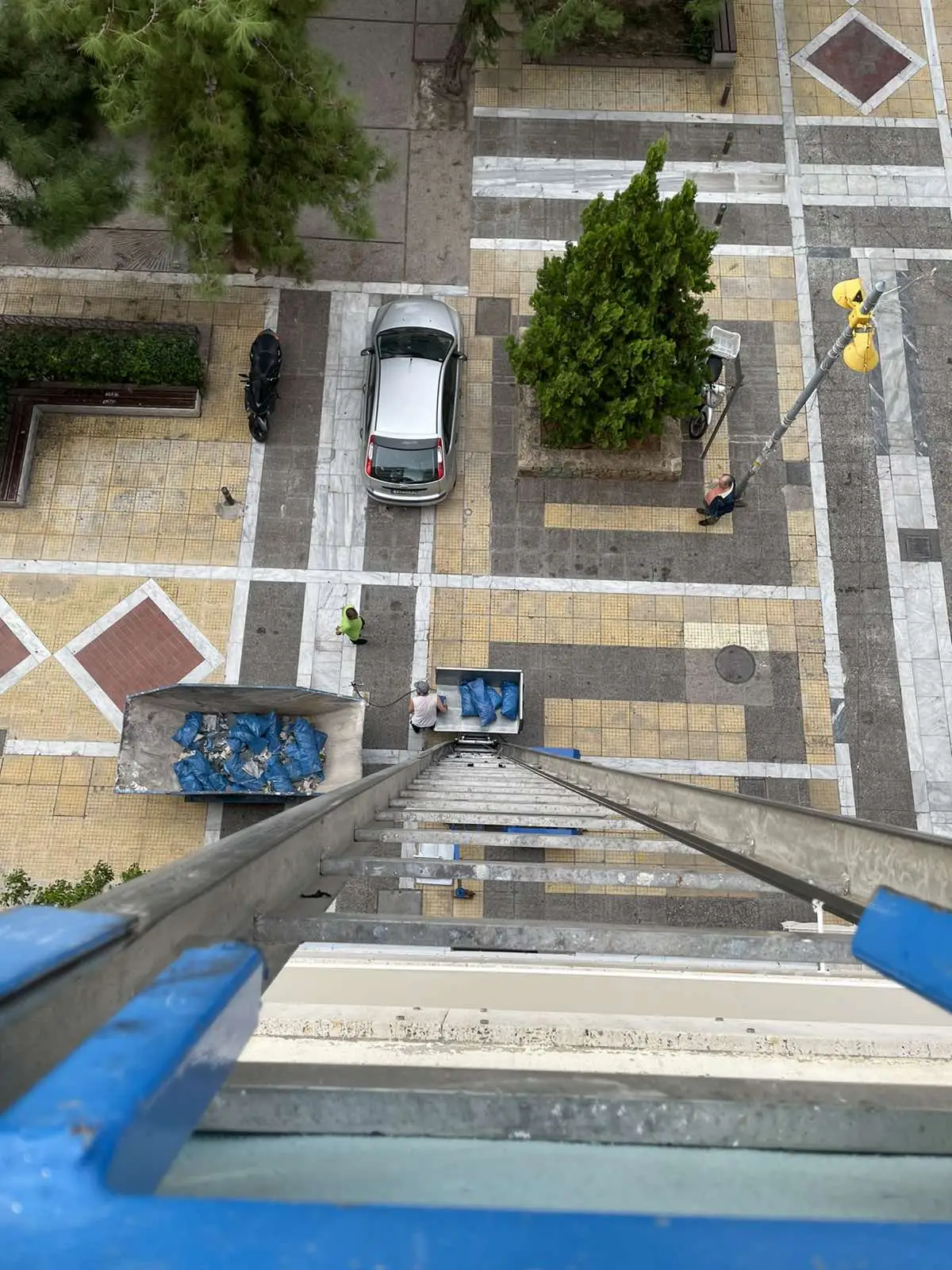 Crane-equipped vehicle removing bagged construction waste from an apartment renovation in Nea Smyrni